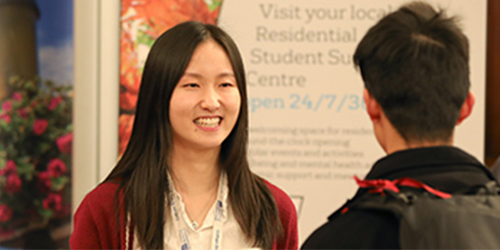 A student talking to a University member of staff at a stall during an event.